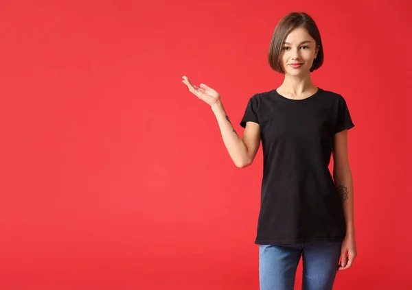 Piękna Młoda Kobieta Stylowej Koszulce Pokazując Coś Tle Koloru — Zdjęcie stockowe