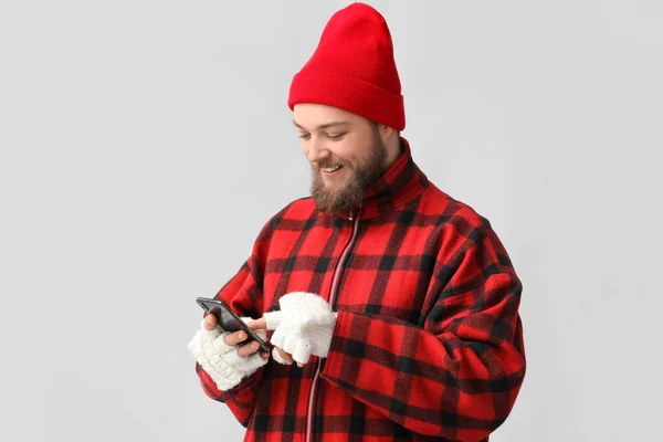 Молодой Бородатый Мужчина Теплых Перчатках Помощью Мобильного Телефона Светлом Фоне — стоковое фото