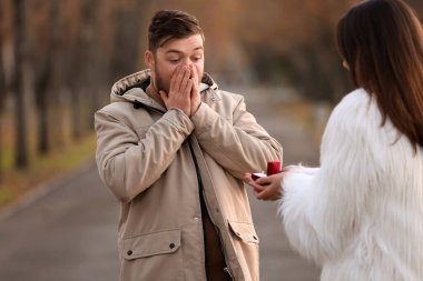 Genç bir kadın parkta sürpriz erkek arkadaşına evlenme teklif ediyor.