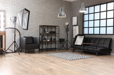 Raflar, kanepe ve profesyonel ekipmanlarla modern fotoğraf stüdyosunun içinde.