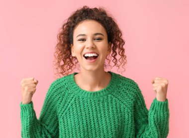 Pembe arka planda yeşil kazaklı mutlu Afro-Amerikan kadın