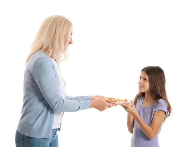 一个成熟的女人把装有饼干的盘子送给她的小孙女 背景是白色的 — 图库照片