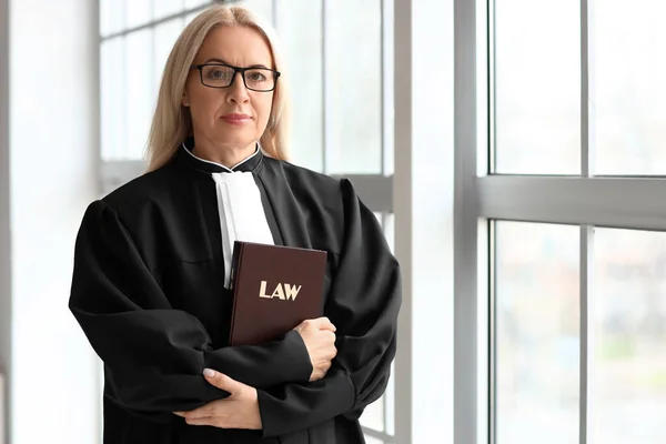 Juez Madura Con Libro Leyes Cerca Ventana Sala Del Tribunal —  Fotos de Stock