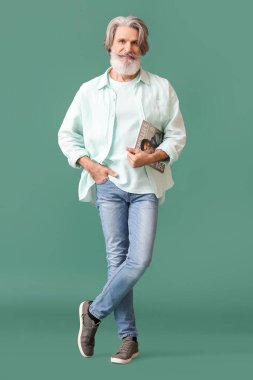 Yeşil arka planda dergisi olan son sınıf sakallı adam.