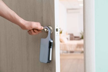 Otel odasında askılı kapıyı açan adam, yakın plan.