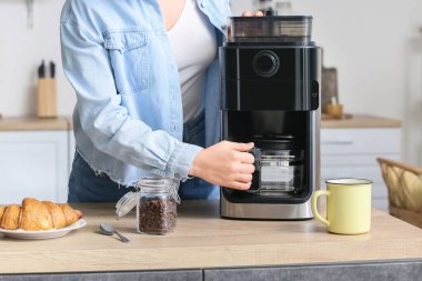 Mutfakta modern kahve makinesi olan genç bir kadın.