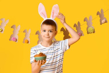 Tavşan kulaklı şirin bir çocuk ve sarı arka planda Paskalya pastası.