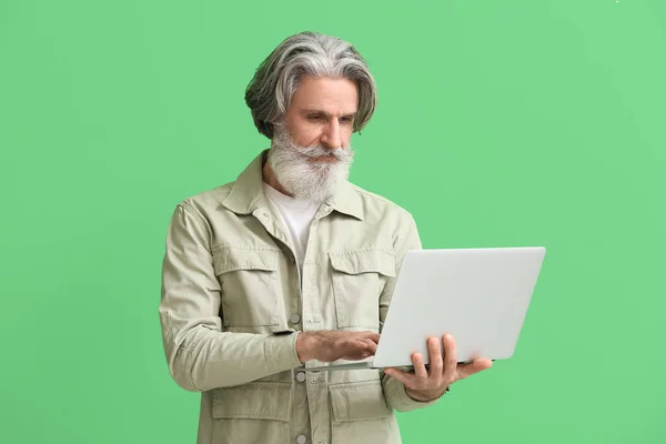 老年人在绿色背景下使用笔记本电脑 — 图库照片