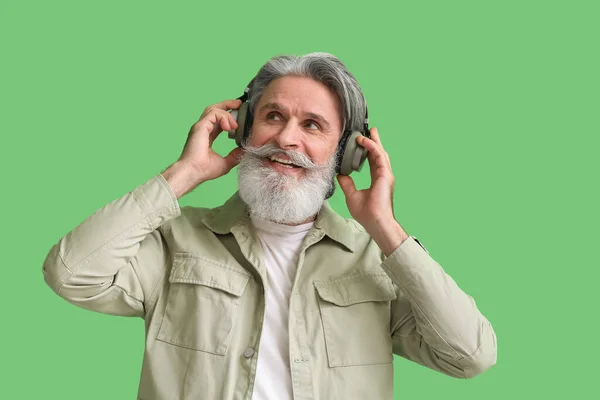 Senior Słuchawkach Słuchający Muzyki Zielonym Tle — Zdjęcie stockowe