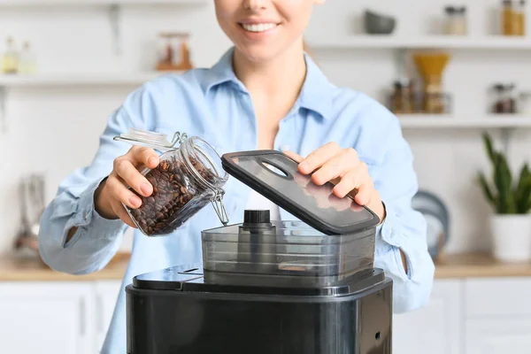 若い女性は台所でコーヒーマシンに豆を入れて — ストック写真
