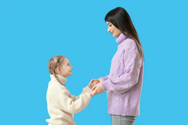 Mała Dziewczynka Jej Matka Ciepłych Swetrach Trzymając Się Ręce Niebieskim — Zdjęcie stockowe