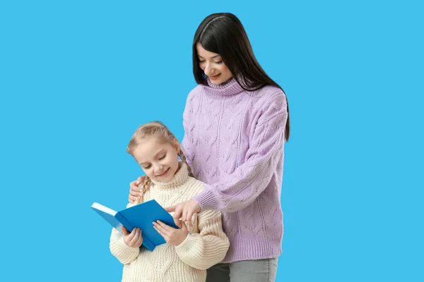 Dziewczynka Jej Matka Ciepłych Swetrach Czytają Książkę Niebieskim Tle — Zdjęcie stockowe