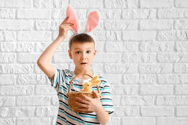かわいいです男の子とともにウサギの耳とイースターバスケット上の白いレンガの背景 — ストック写真