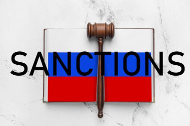 Sayfalar dolusu Rus bayrağı, yargıç tokmağı ve ışık arkaplan üzerinde SANCTIONS sözcüğü içeren açık bir kitap