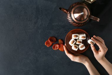 Lezzetli Türk zevkine sahip kadın elleri, koyu arkaplanda kurutulmuş kayısılar ve çay