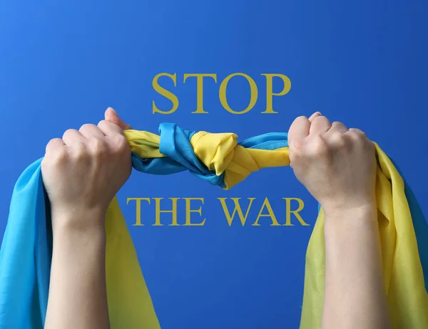 举着乌克兰国旗的手和蓝色背景的文字停止战争 — 图库照片