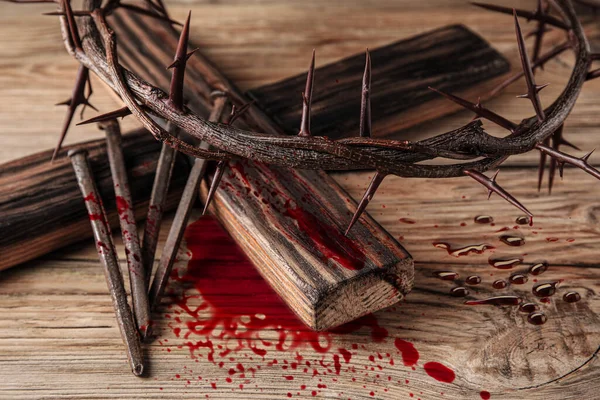 Crown of thorns, cross and nails covered with blood on wooden background. Jesus Christ\'s sacrifice and atonement of our sins