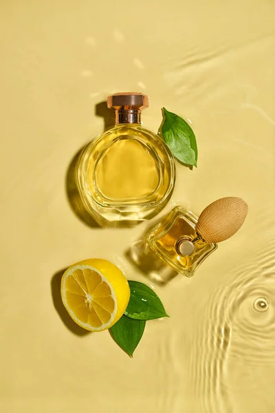薄い色の背景に水の中に柑橘類の香水のボトル トップビュー — ストック写真