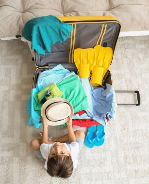 Küçük çocuk evde bavul hazırlıyor.