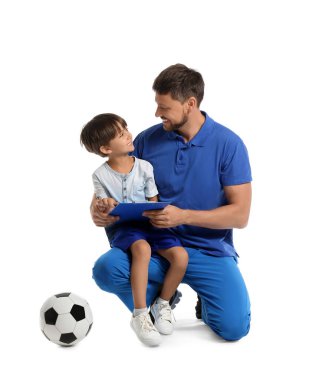 Beyaz arka planda küçük bir çocuk ve futbol topu olan erkek antrenör.