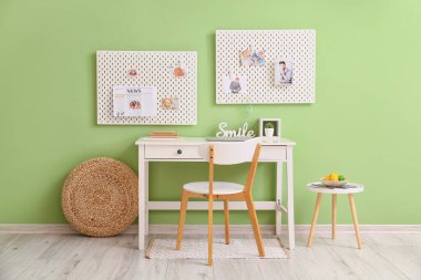 Yeşil duvarda farklı malzemeler ve tahta olan modern işyeri.