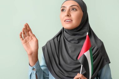 Yeşil arka planda BAE bayrağı olan güzel Müslüman kadın.