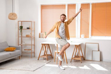 Kulaklıklı genç adam evde dans ediyor.