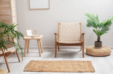 Koltukları, çiçekleri ve hasır halısı olan aydınlık oturma odasının içinde.