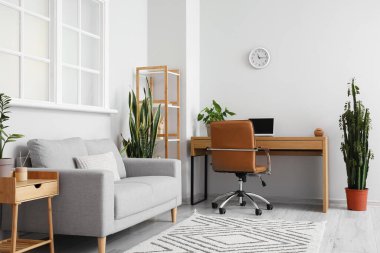 Gri kanepesi ve modern işyeri olan aydınlık oturma odasının içi.