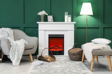 Şık oturma odasının içinde şömine rafı, odun ve koltuk var.