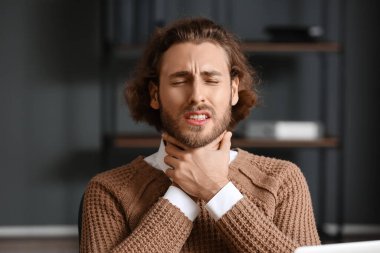 Ofiste boğazı ağrıyan hasta bir adam.