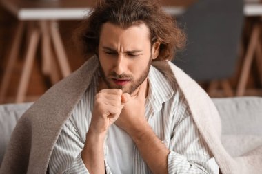 Evde boğazı ağrıyan hasta bir adam.