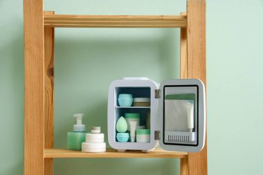 Odadaki rafta küçük bir kozmetik buzdolabı.