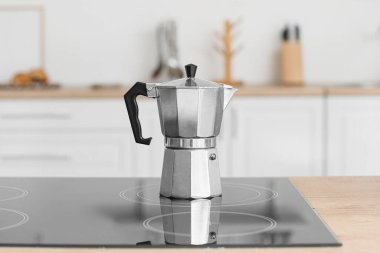 Mutfakta elektrikli ocağın üzerinde kahve makinesi var.