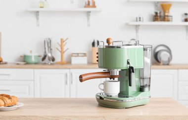 Mutfaktaki masada fincanı olan modern kahve makinesi.