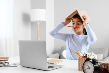 Komik küçük Asyalı kız evde online öğretmenle edebiyat okuyor.