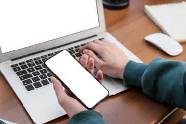 Cep telefonu tutan ve dizüstü bilgisayarla çalışan kadın, yakın plan.