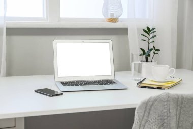 Modern laptop ve cep telefonuyla aydınlatma odasında rahat bir iş yeri