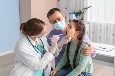 Doktor klinikte boğazı ağrıyan küçük bir kızı muayene ediyor.
