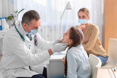 Doktor klinikte boğazı ağrıyan küçük bir kızı muayene ediyor.