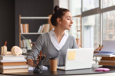 Güzel genç bayan kütüphanede çalışıyor.