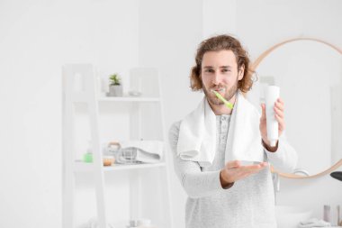 Banyoda dişlerini macunla fırçalayan yakışıklı genç adam.