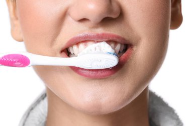 Beyaz arka planda diş fırçalayan genç kadın, yakın plan.