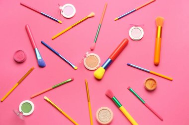 Makyaj fırçaları ve pembe arka planda farklı göz falı olan kompozisyon