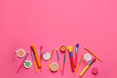 Makyaj fırçaları ve pembe arka planda farklı göz falı olan kompozisyon