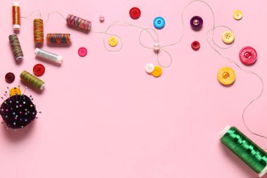 Pembe arka planda iplik makaraları, top raptiyeleri ve düğmeler