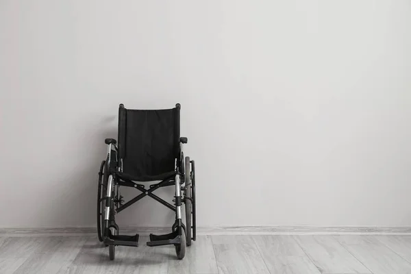 stock image Empty wheelchair near light wall