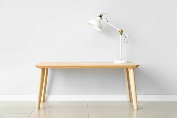 轻墙附近木制桌子上的现代白灯 — 图库照片