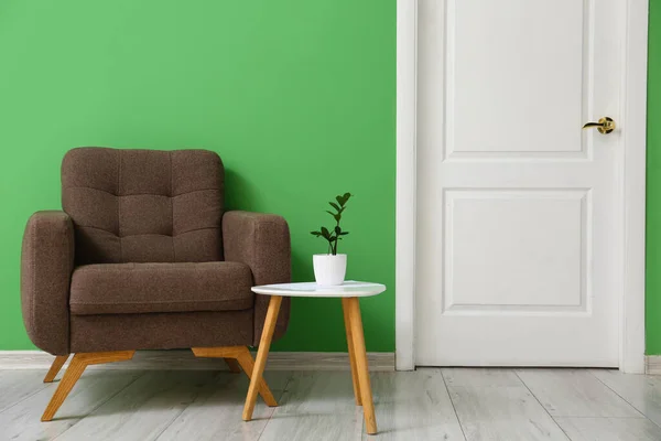 Кресло Стол Цветочным Горшком Возле Зеленой Стены — стоковое фото