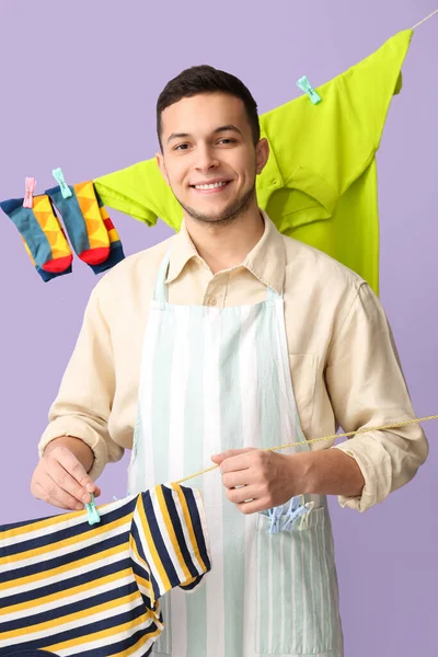 Young Man Hanging Clean Shirt Clothespin Lilac Background — Stock Photo, Image